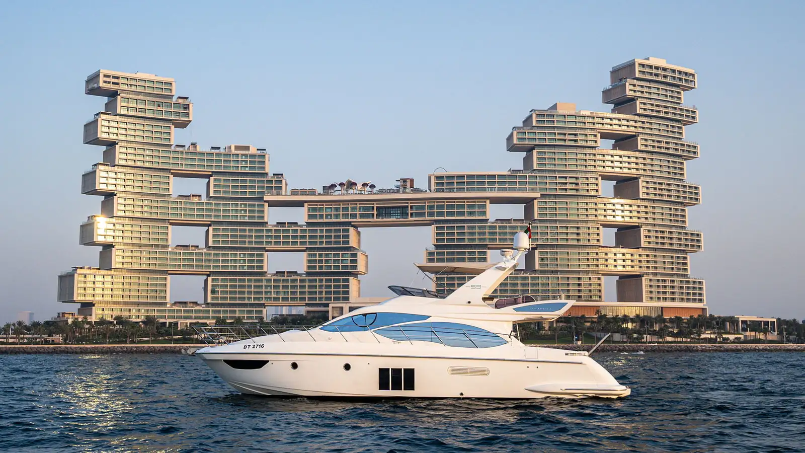 Yacht en mer au large de Dubaï au coucher du soleil, le soleil descendant derrière Palm Jumeirah
